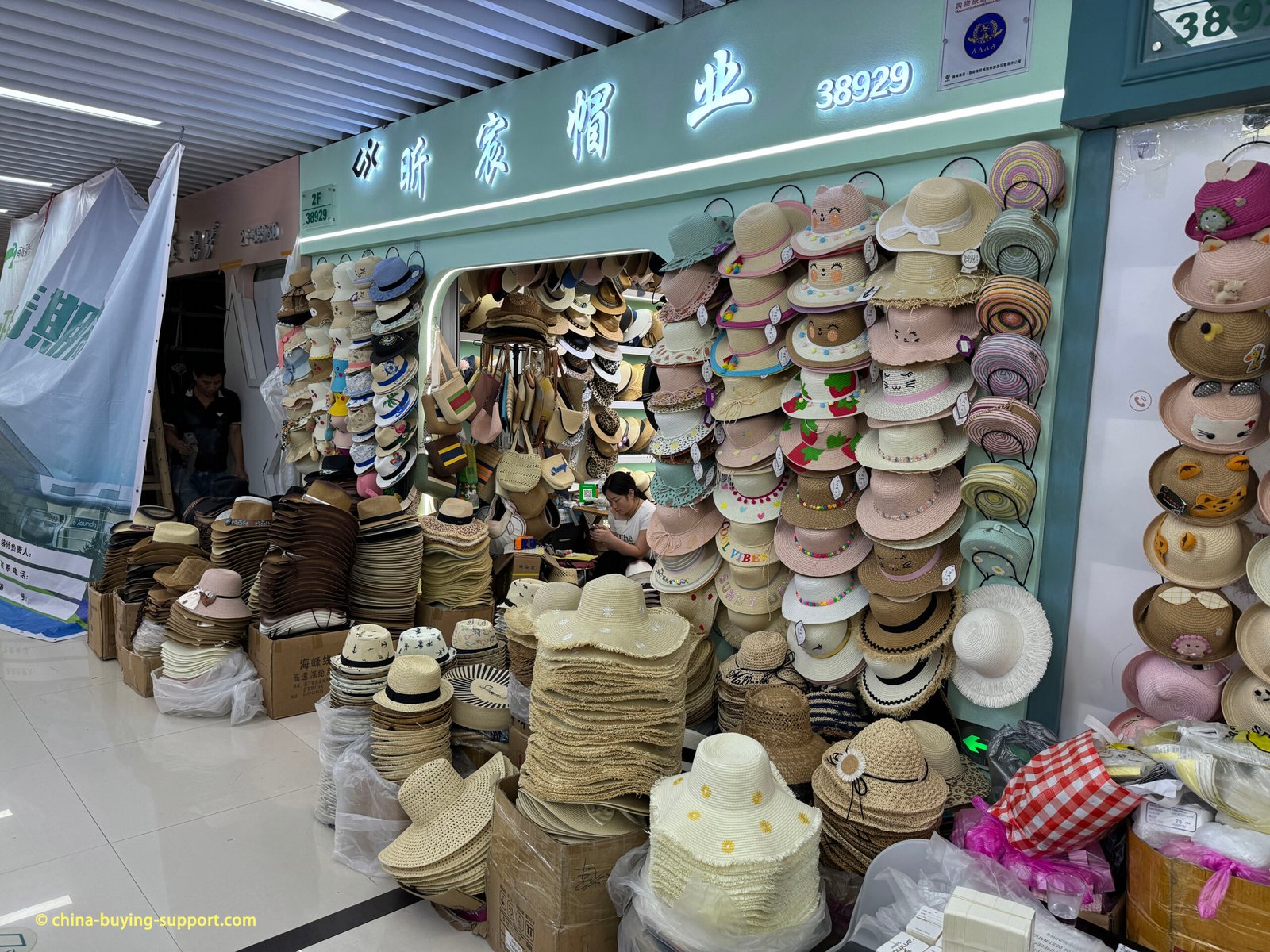 Straw sun hats and kids hats stacked at a hat wholesaler, District 4, in Yiwu Market