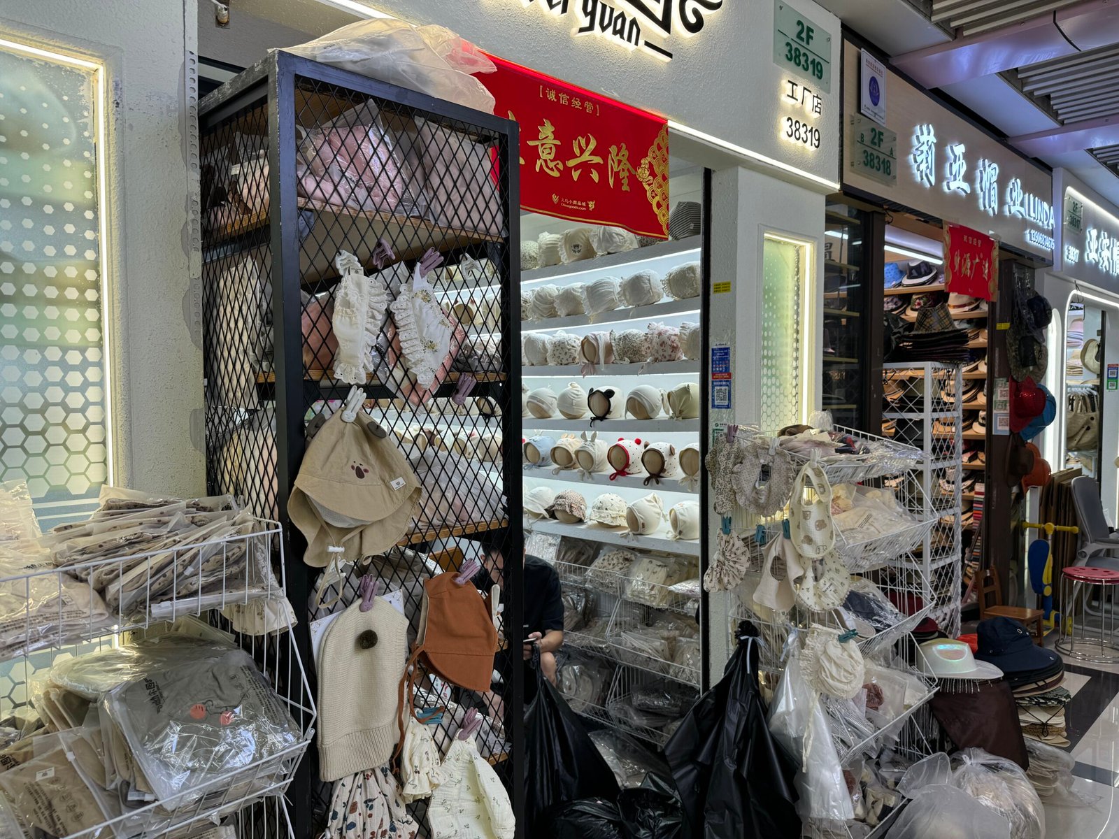 Yiwu wholesale supplier with shelves of baby bonnets, lace headbands, sun hats and knit caps in cream and beige tones