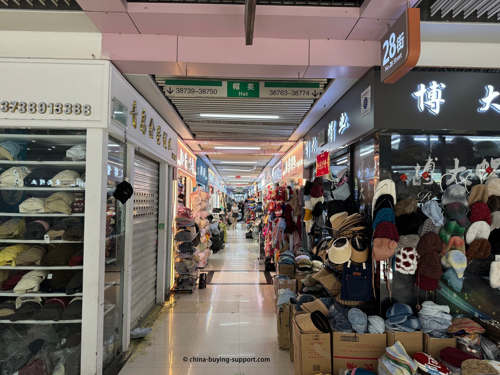 A long aisle at Yiwu International Trade City’s hat section (No. 28 Street), lined with wholesale shops selling bucket hats, visors, baseball caps and knit beanies