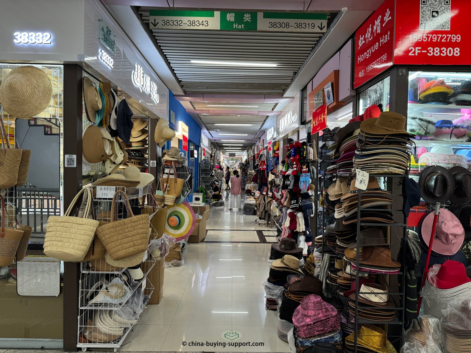 Yiwu Hat Market aisle with racks of straw hats, cowboy/fedora hats, felt styles, beanies