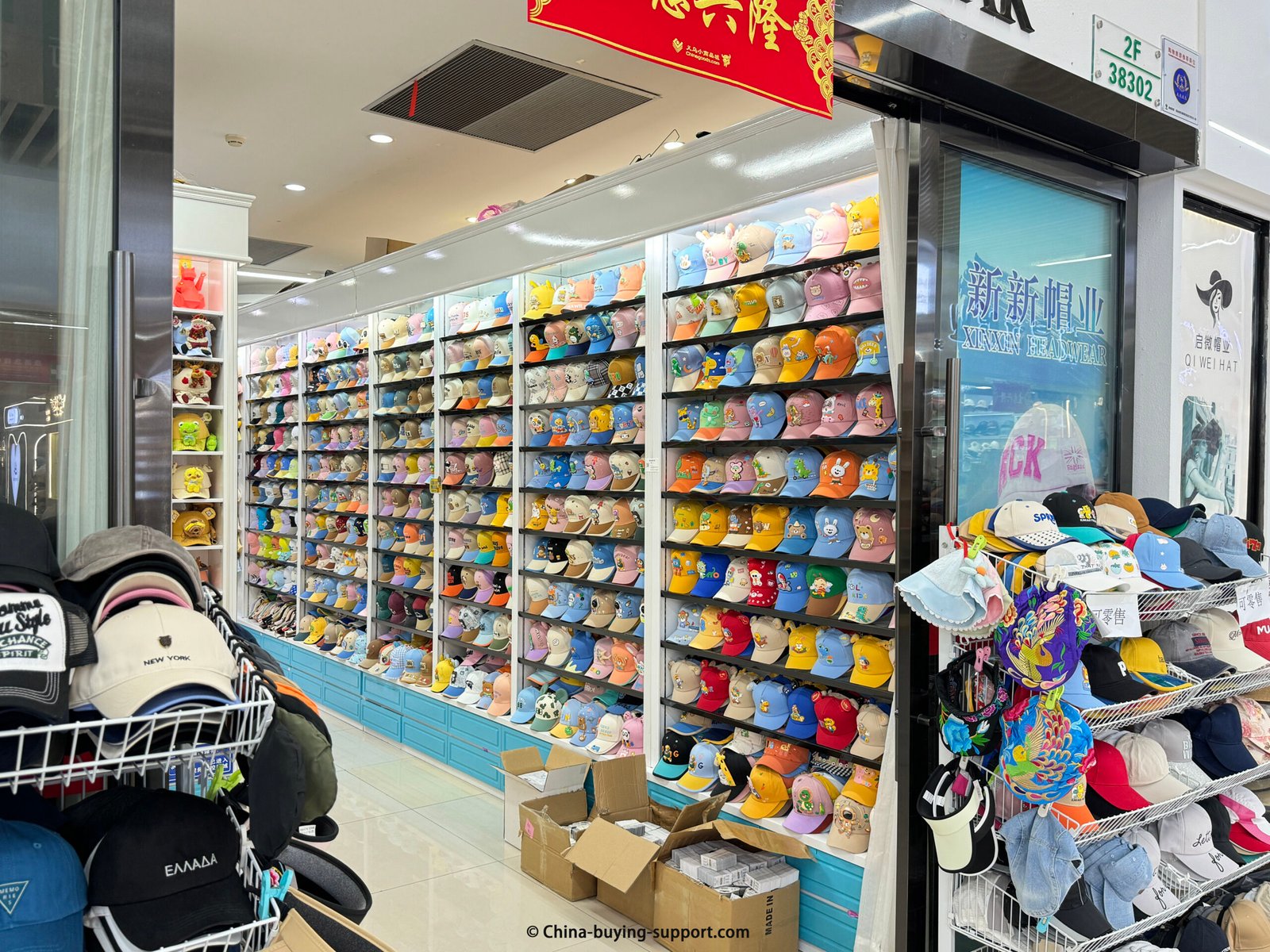 Yiwu wholesale shop with walls of children’s cartoon baseball caps, visors and bucket hats in pastel colors—Xinxin Hatwear storefront.