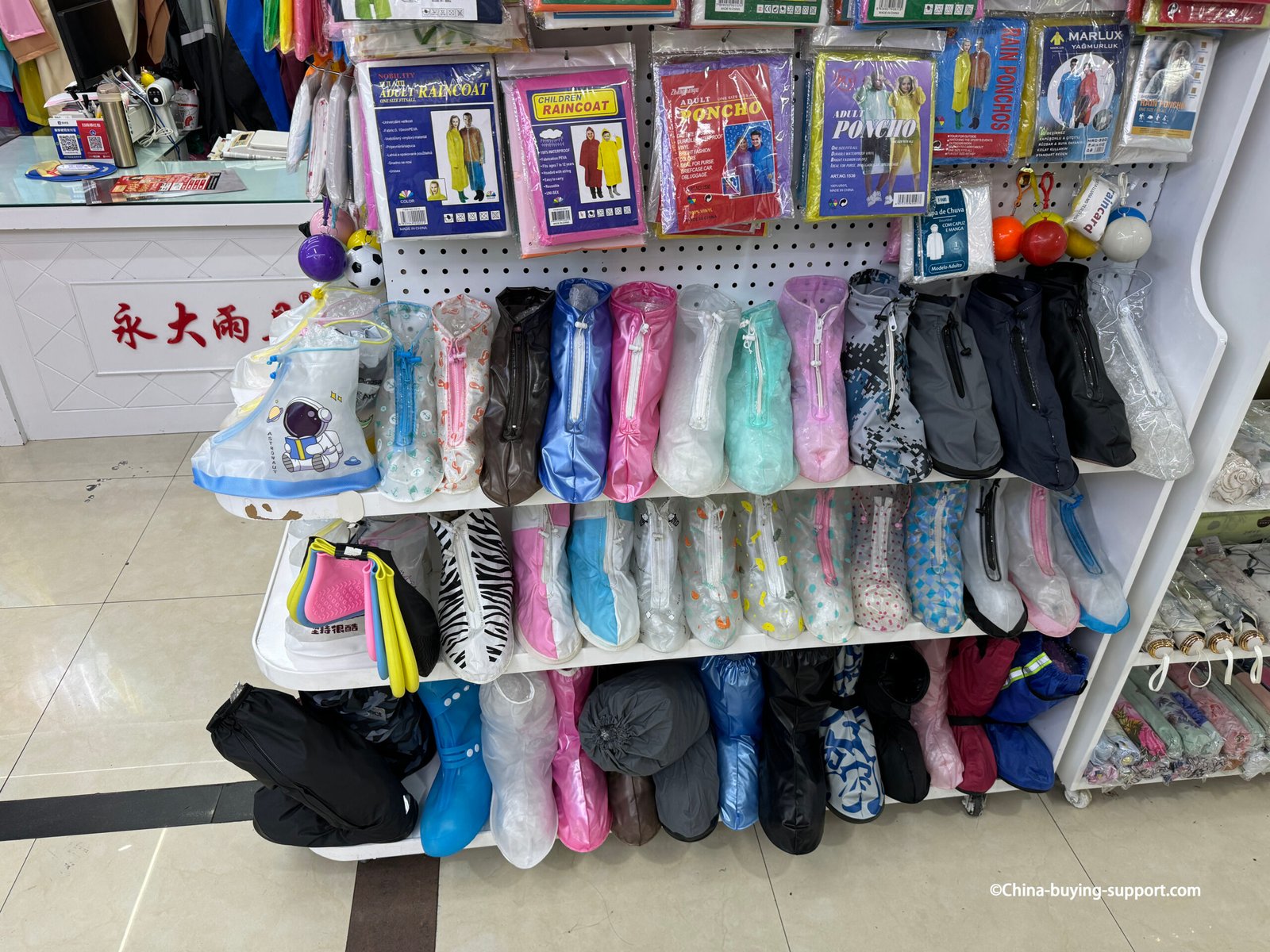 yiwu rainwear shelf with waterproof zippered shoe covers in assorted colors and prints, packaged raincoats and ponchos