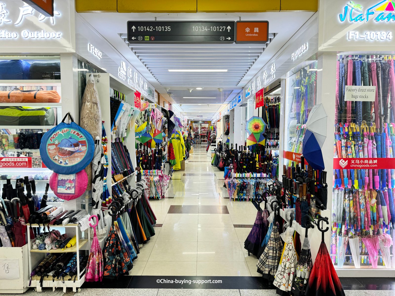Aisle of umbrella shops at Yiwu International Trade City, China—racks of colorful folding, reverse and straight umbrellas.