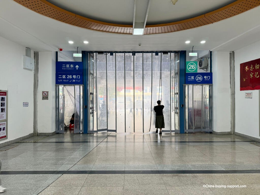 yiwu umbrella wholesale entrance, district 2 gate 26 with clear pvc strip curtains, blue bilingual signs, person pulling plastic panel