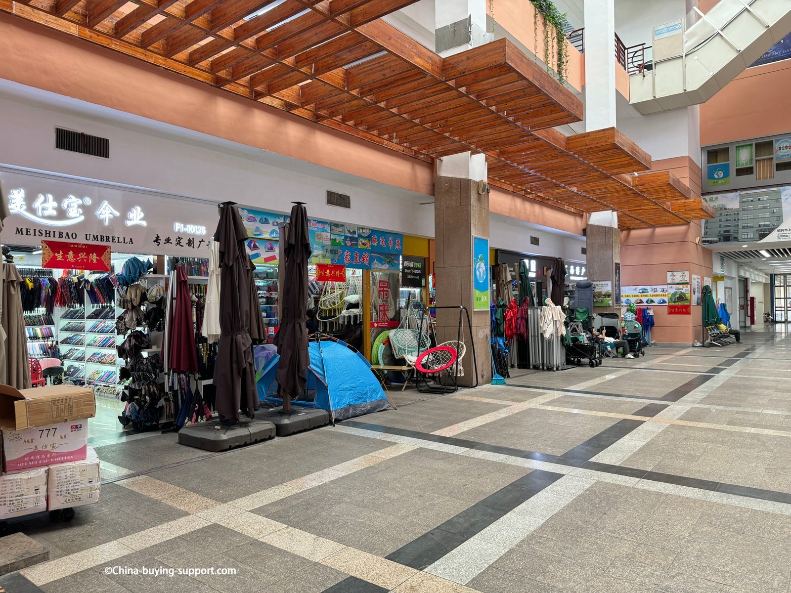 yiwu district 2 umbrella storefront, patio parasols on bases, blue camping tent, hanging egg chairs, racks of rain umbrellas