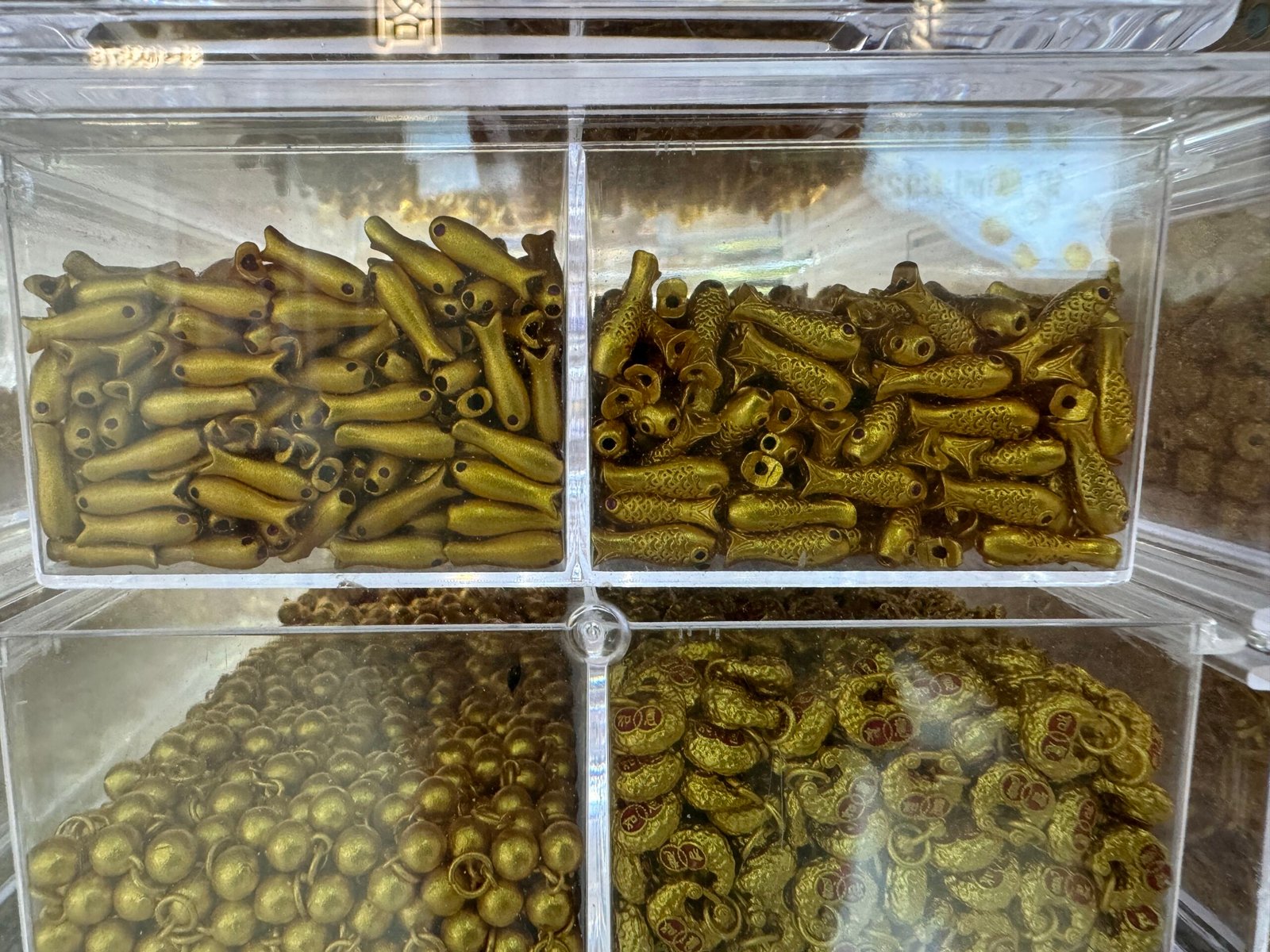 Antique brass fish beads with threading holes plus bell-type charms and enamel lucky coin rings from Yiwu copper supplier.