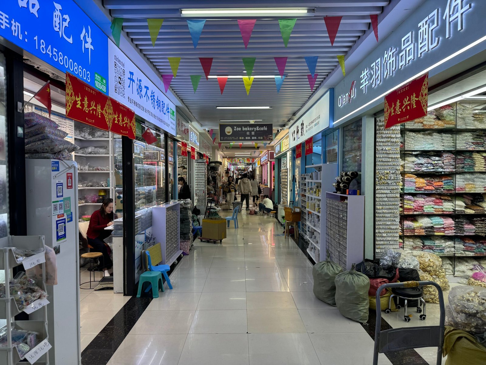Long aisle of Yiwu accessories market lined with bead shops, findings drawers and shelves of bulk packaged trims.