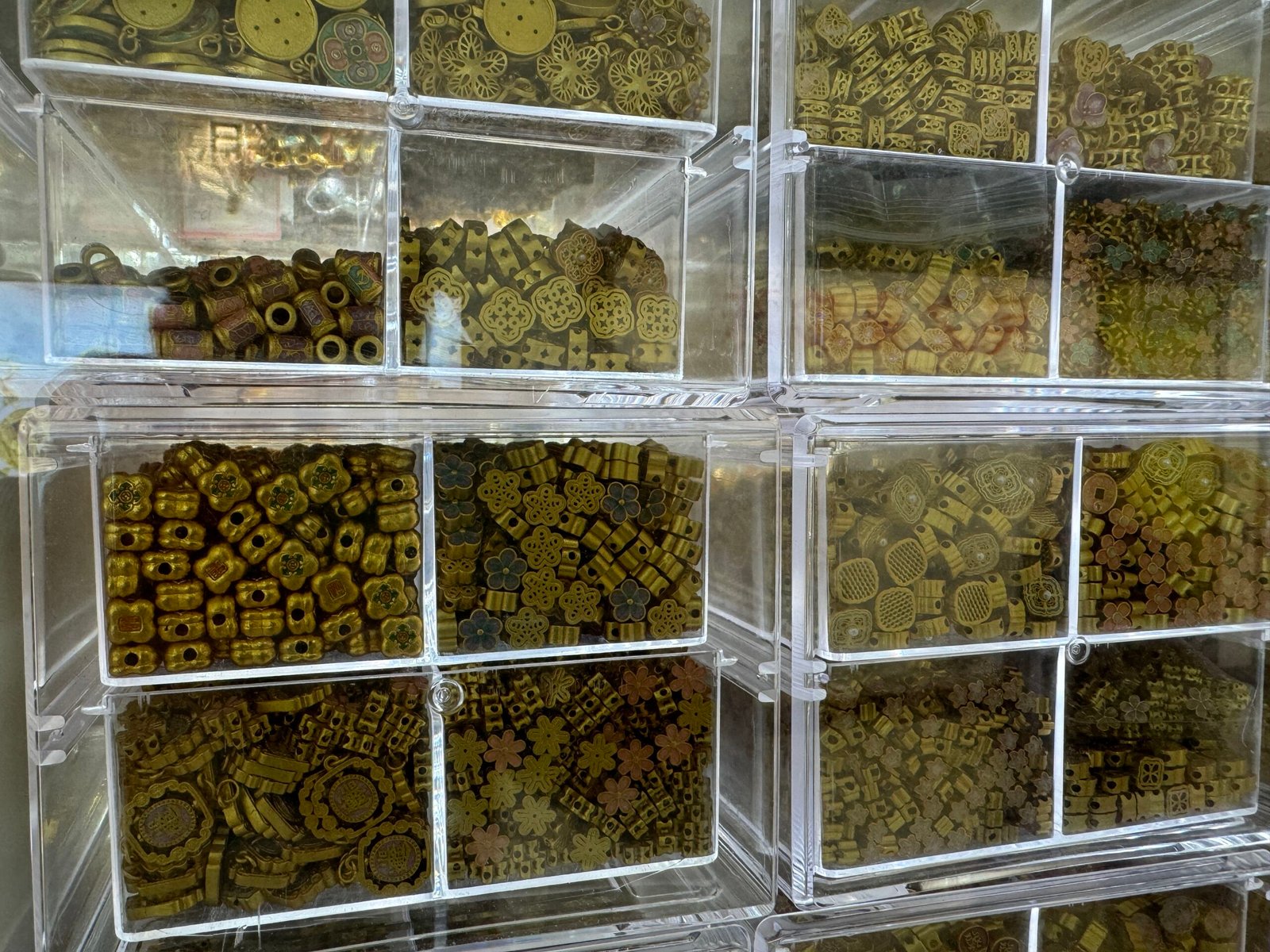 Mixed antique brass copper beads in clear drawers—quatrefoil, flower, barrel and coin spacer shapes from Yiwu wholesale supplier.