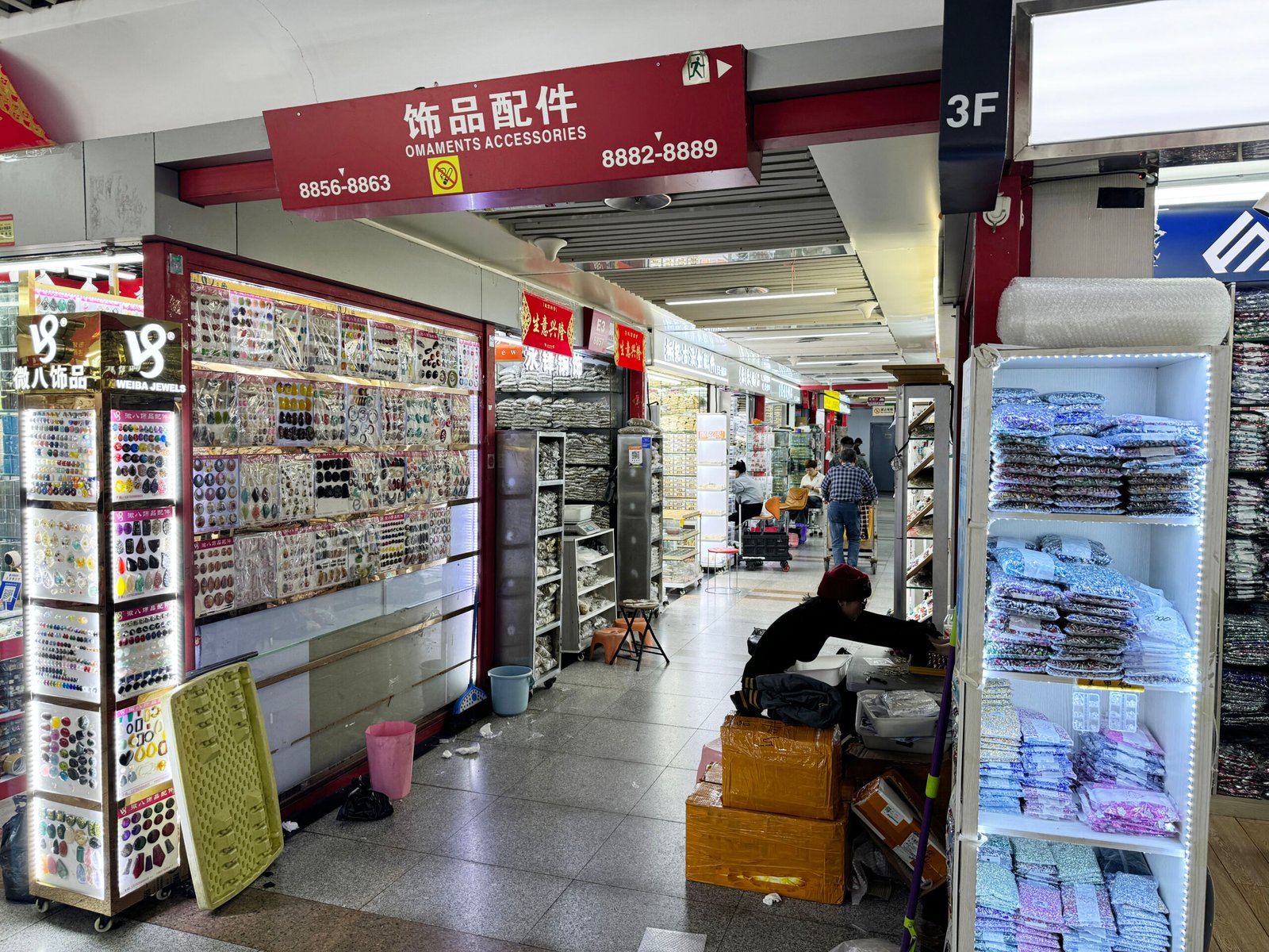 Shelves packed with cabochons, earring hooks, stud bases, and pendant settings in Yiwu market.
