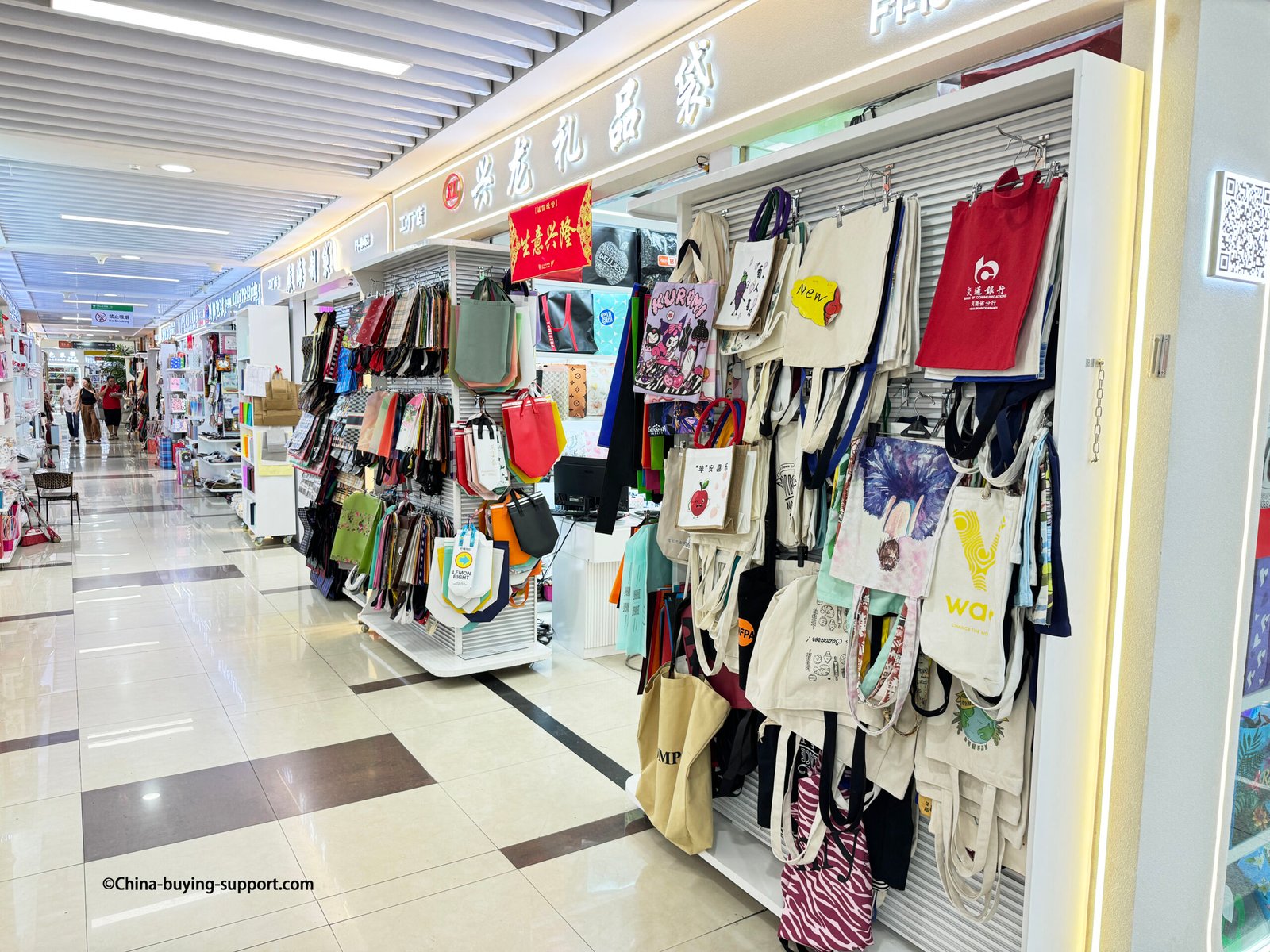 Canvas and non-woven tote bags supplier shop at Yiwu International Trade City District 2, displaying eco-friendly reusable shopping bags and custom printed designs for wholesale buyers.