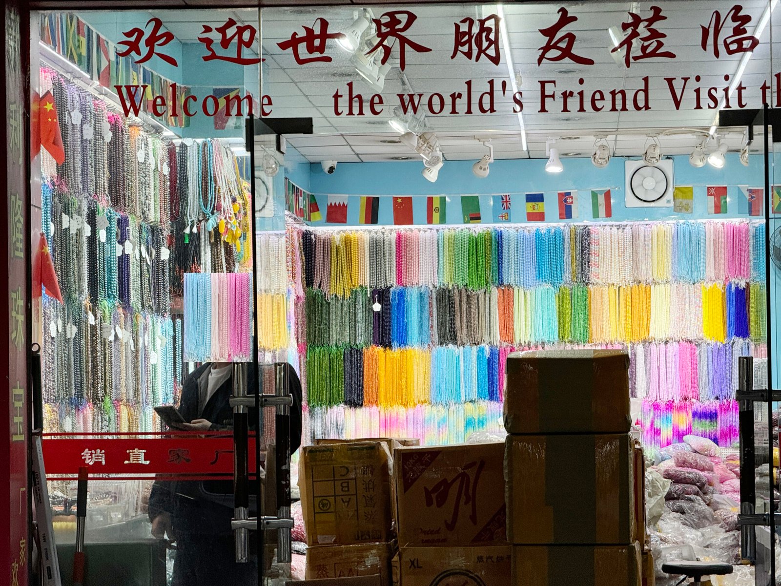 Interior of Yiwu bead wholesale shop with rainbow rows of strands; gemstone, glass and pearl beads for DIY jewelry