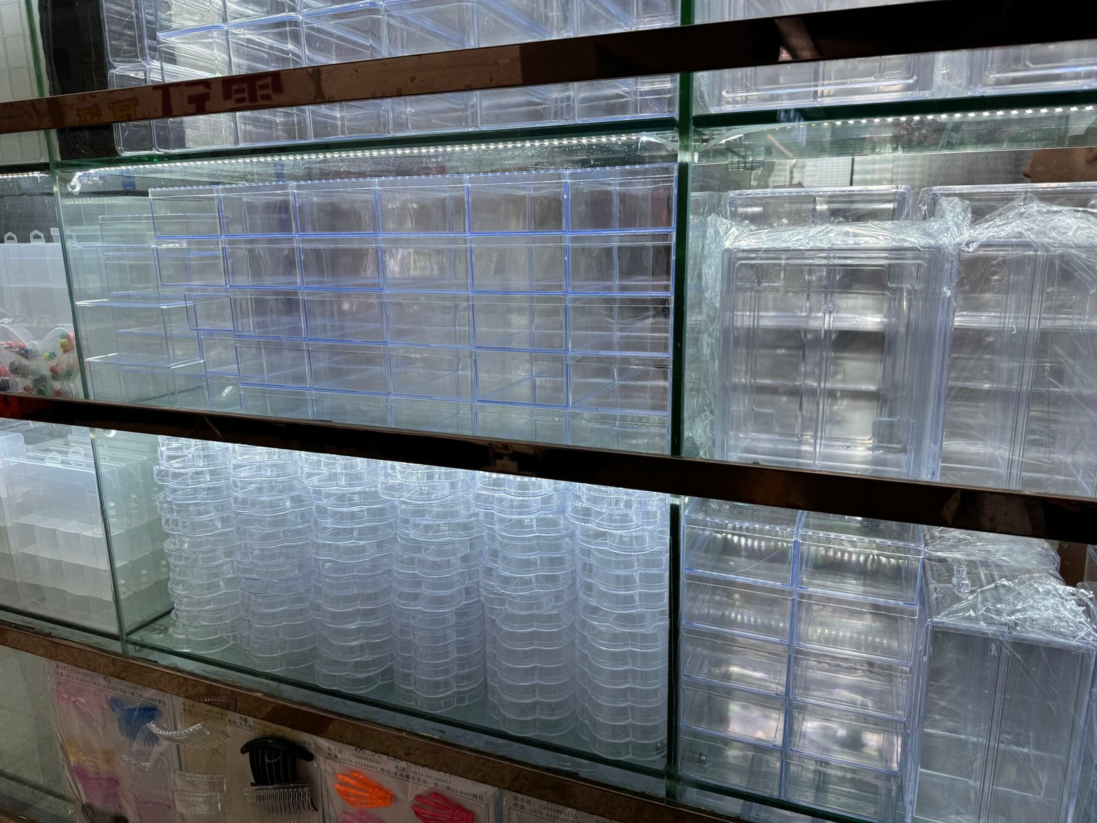Rows of clear plastic grid organizers with multiple compartments and hinged lids.