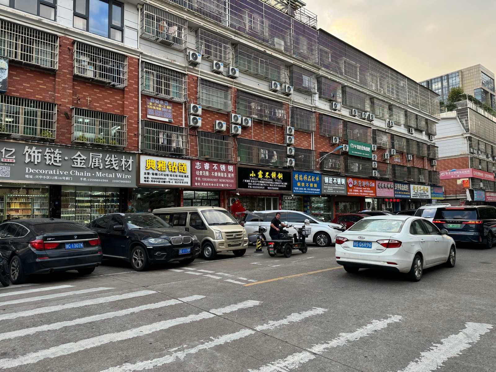 Yiwu shopfronts labeled Decorative Chain and Metal Wire with displays of chain spools and wire for jewelry making and craft use.