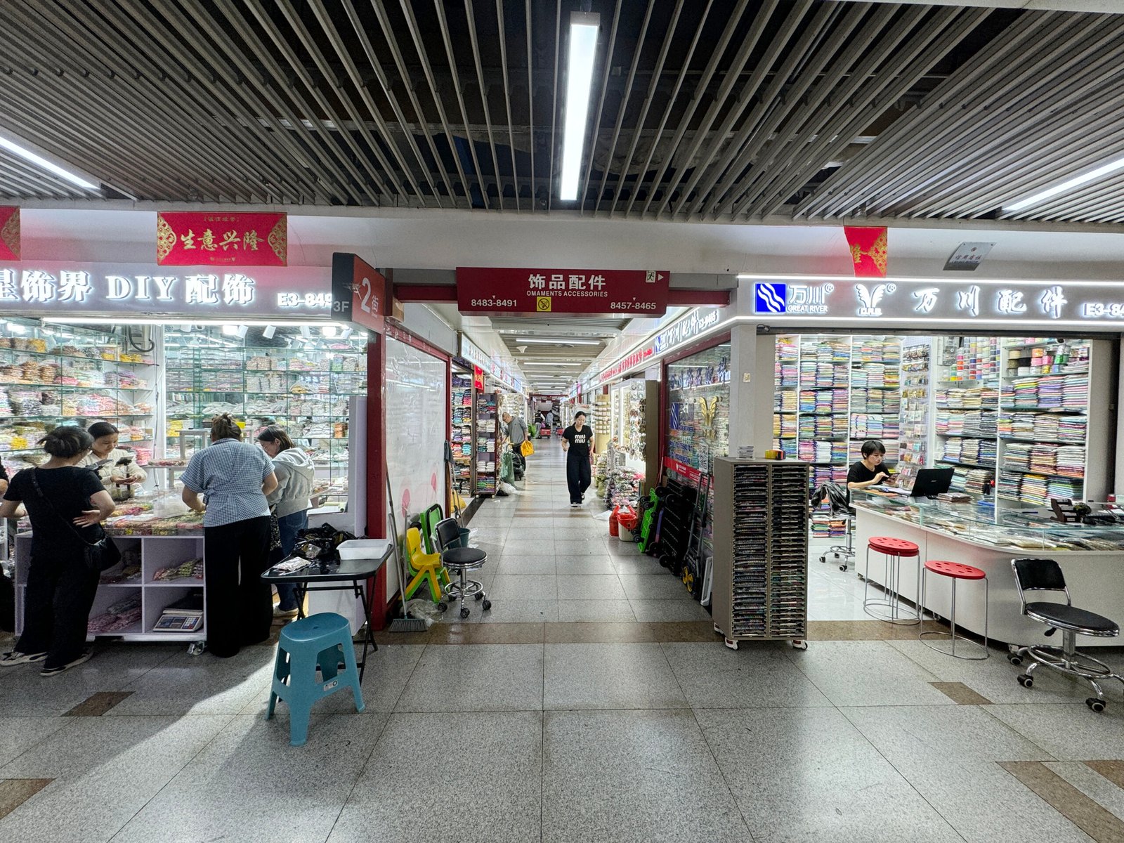 Aisle with DIY accessory shops selling resin flowers, acrylic charms, rhinestones, and seed beads in Yiwu.