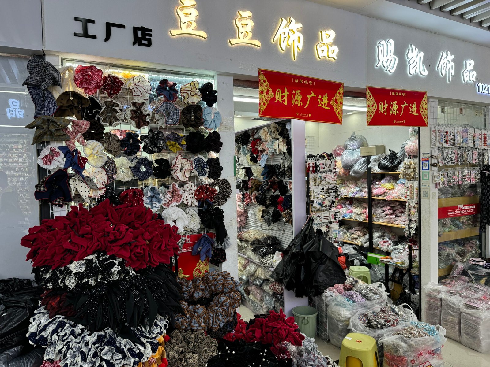 Storefront of Doudou Accessories in Yiwu showing large piles of scrunchies, bows and packaged hair clips for wholesale buyers. Hair Accessories