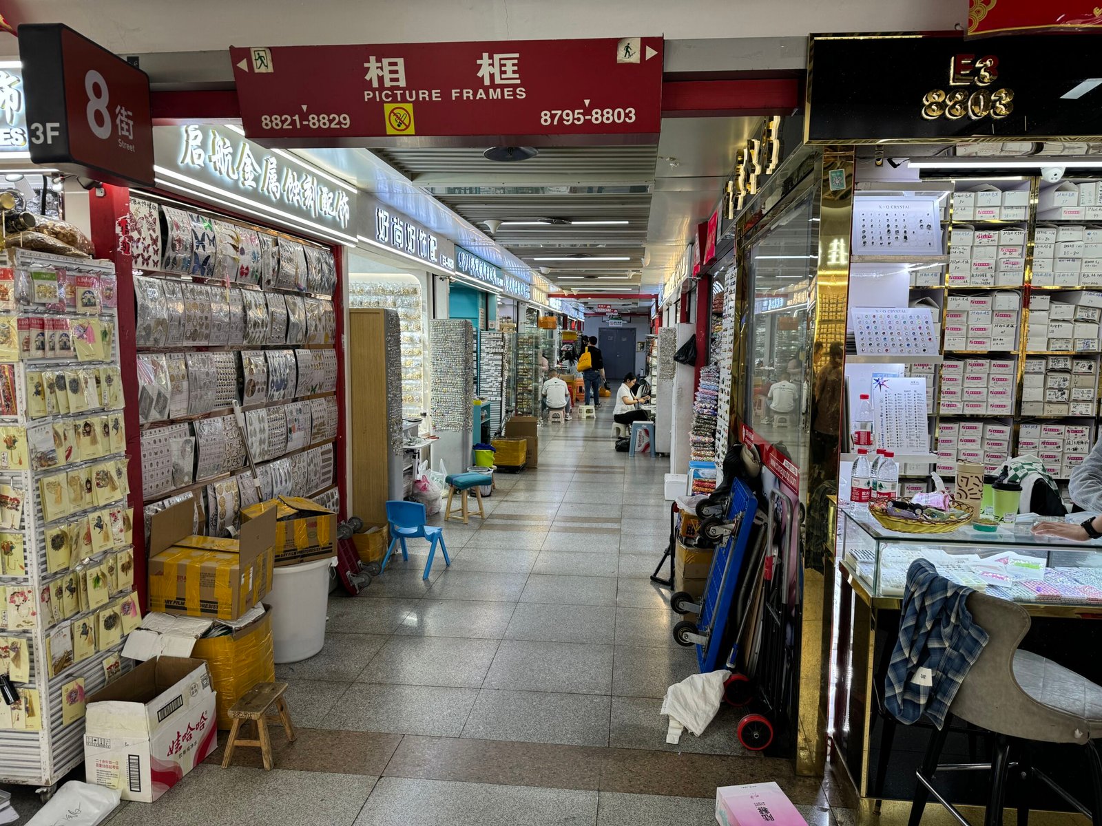 Long aisle showing racks of earring studs, backs, and display cards in Yiwu accessories market.