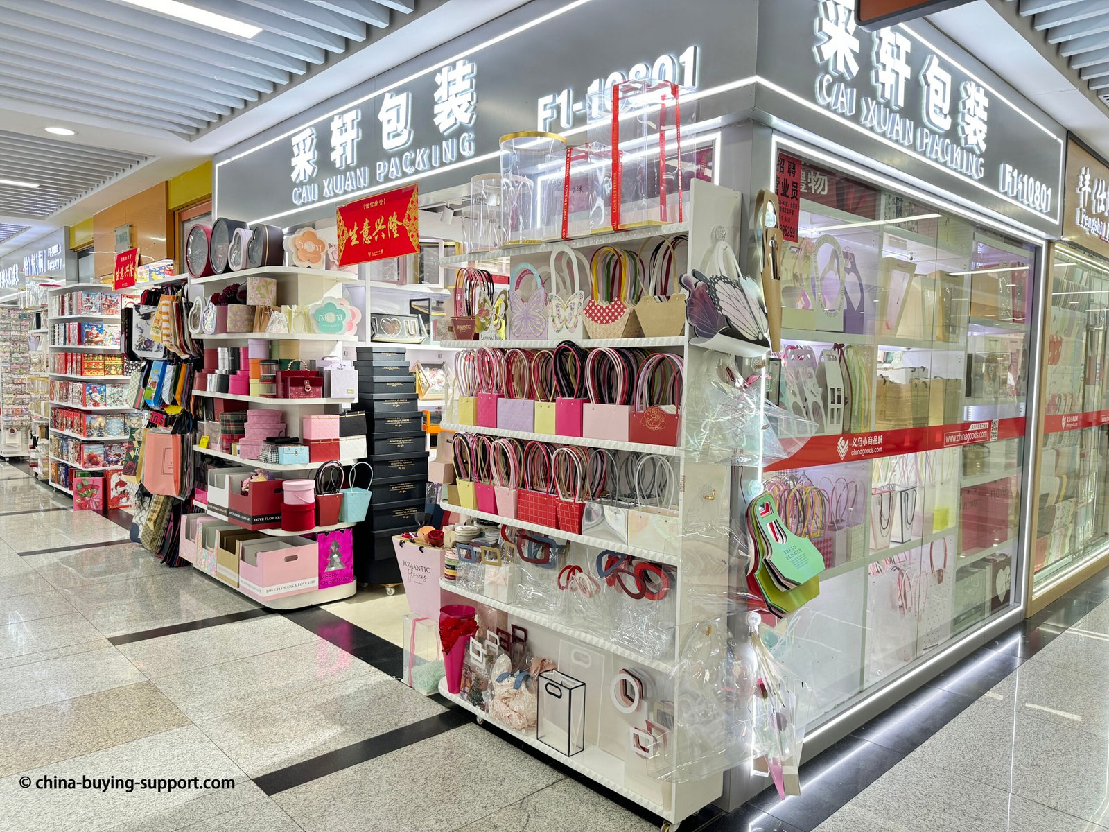 Storefront of a gift bag and gift box supplier at Yiwu International Trade City District 2, China, displaying colorful paper bags, luxury packaging boxes, and custom-designed floral packaging for wholesale buyers.