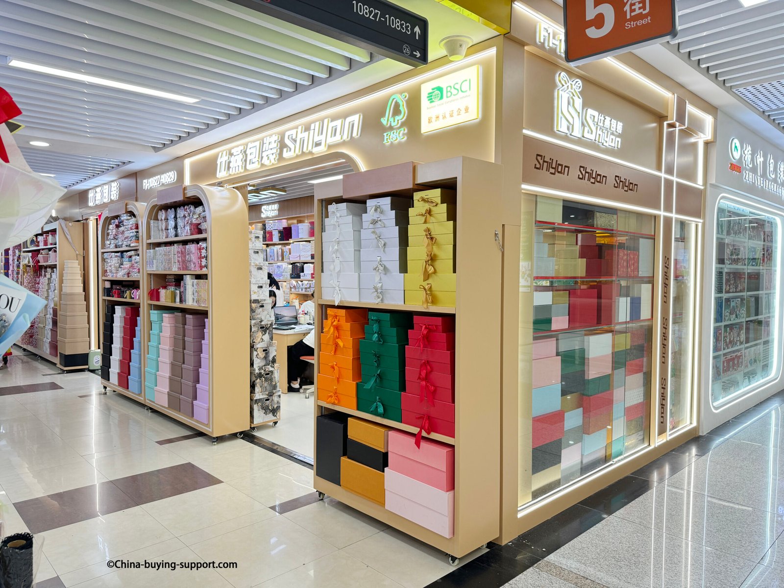 Colorful luxury gift boxes with ribbons and magnetic closures displayed at a gift box supplier shop in Yiwu International Trade City District 2, China, offering wholesale custom packaging solutions.