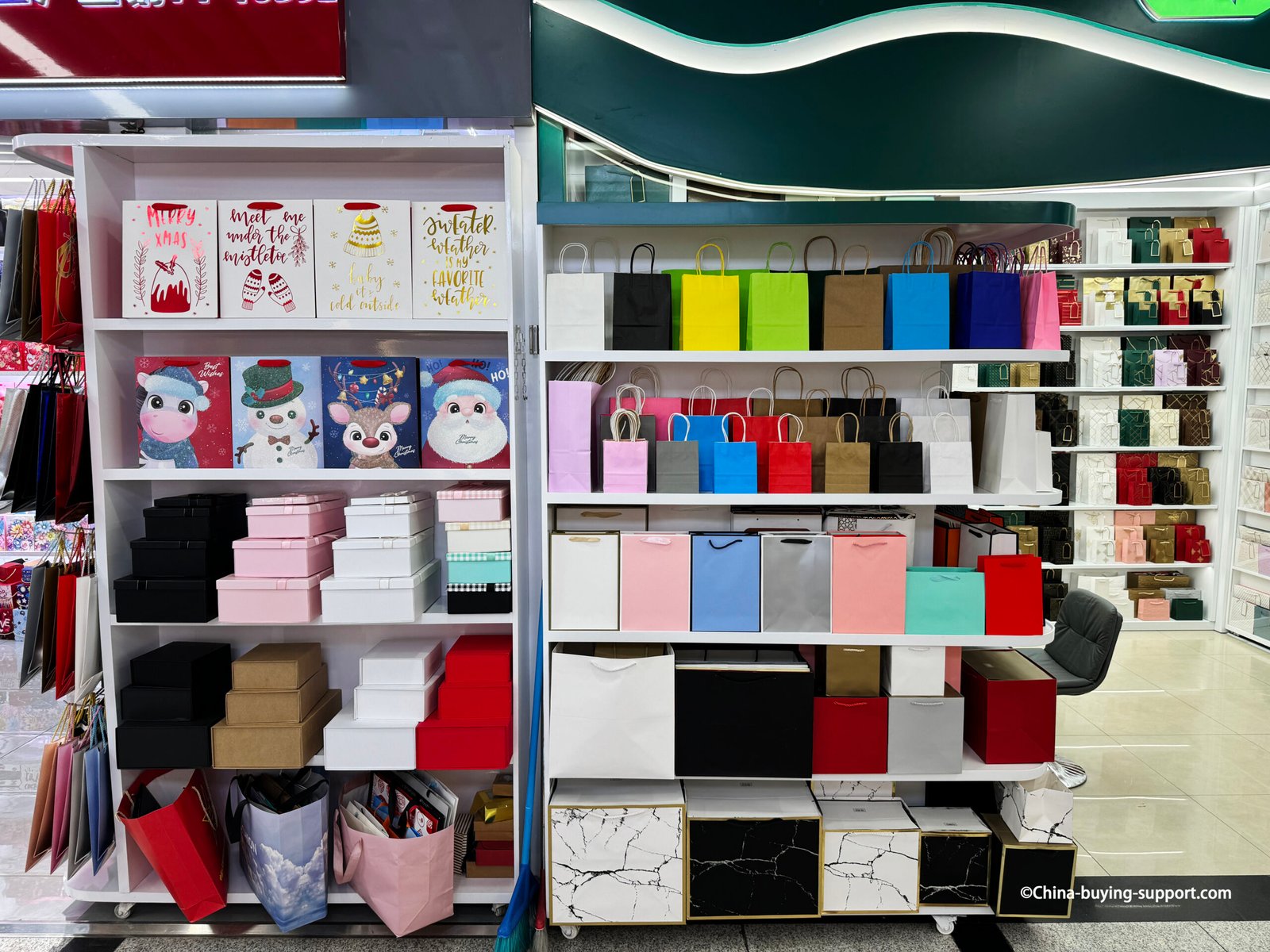 Display of colorful paper bags and gift boxes at Yiwu International Trade City District 2, showing wholesale packaging options in various colors and sizes for retail and gift use.