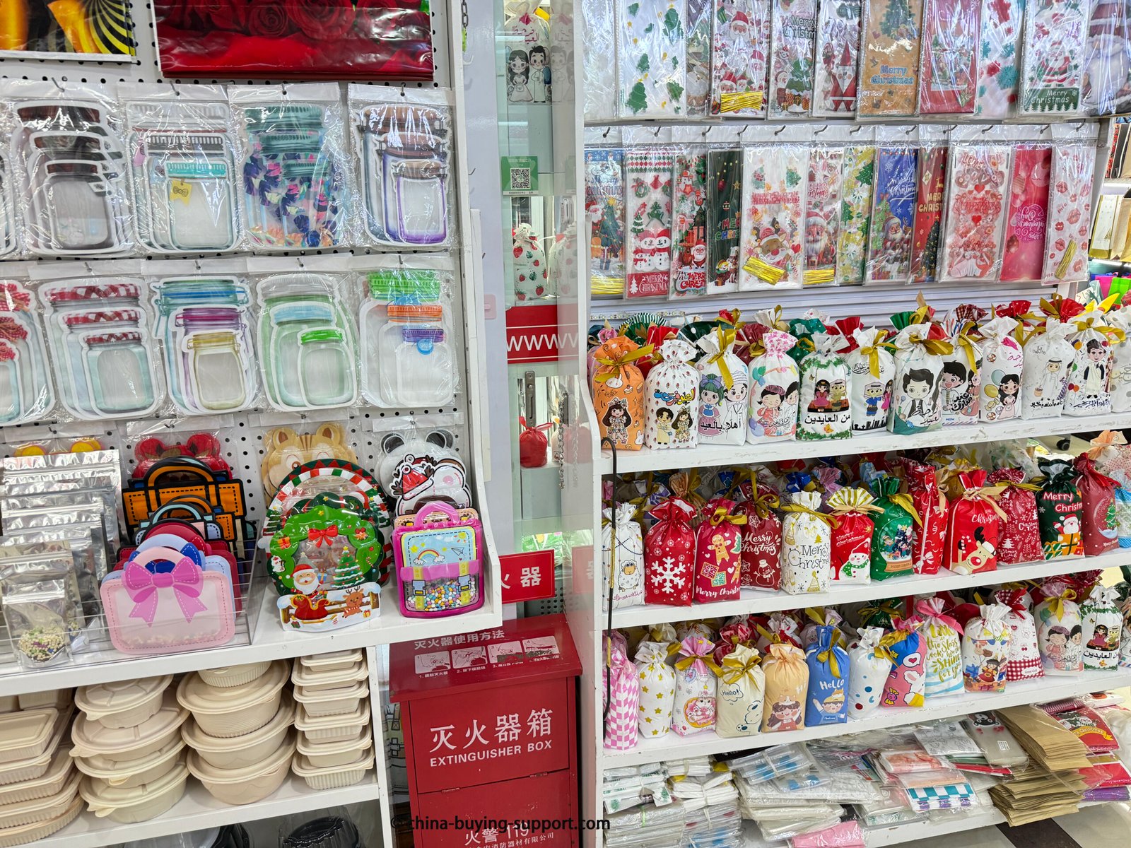 Display shelves inside a Yiwu International Trade City supplier shop, featuring assorted packaging samples including zipper storage bags, Christmas gift pouches, and custom wrapping supplies for wholesale.