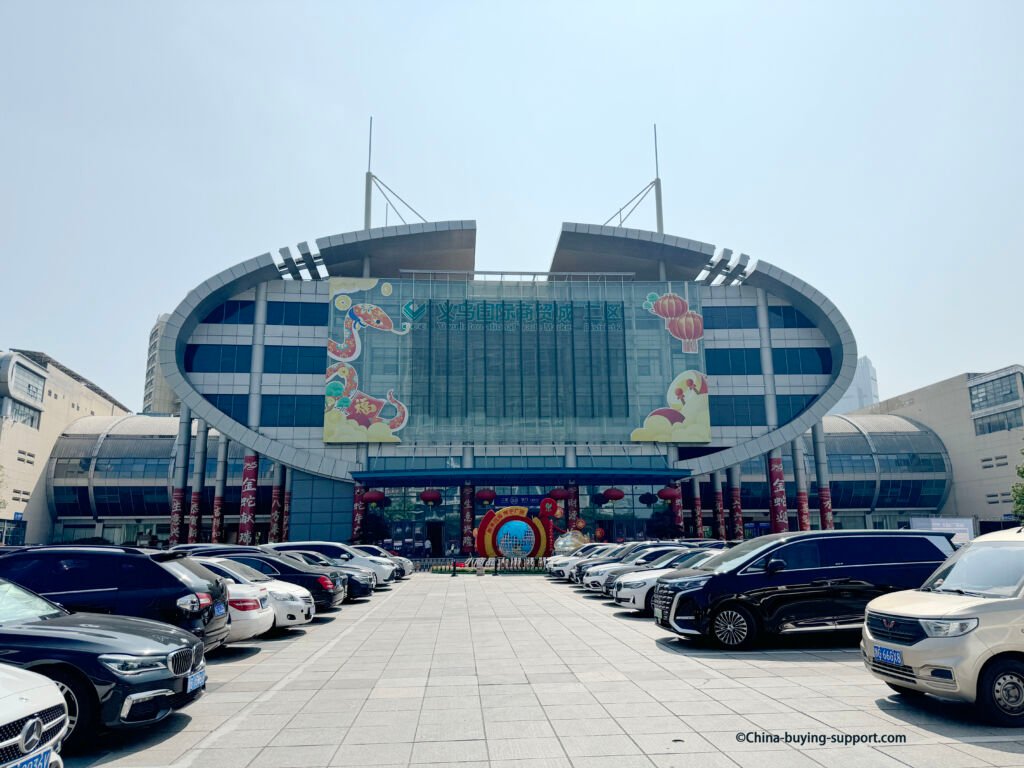 Yiwu International Trade City District 2 West Main Entrance (Gate 33) with oval glass facade, red lanterns and parked cars, Yiwu, China.
