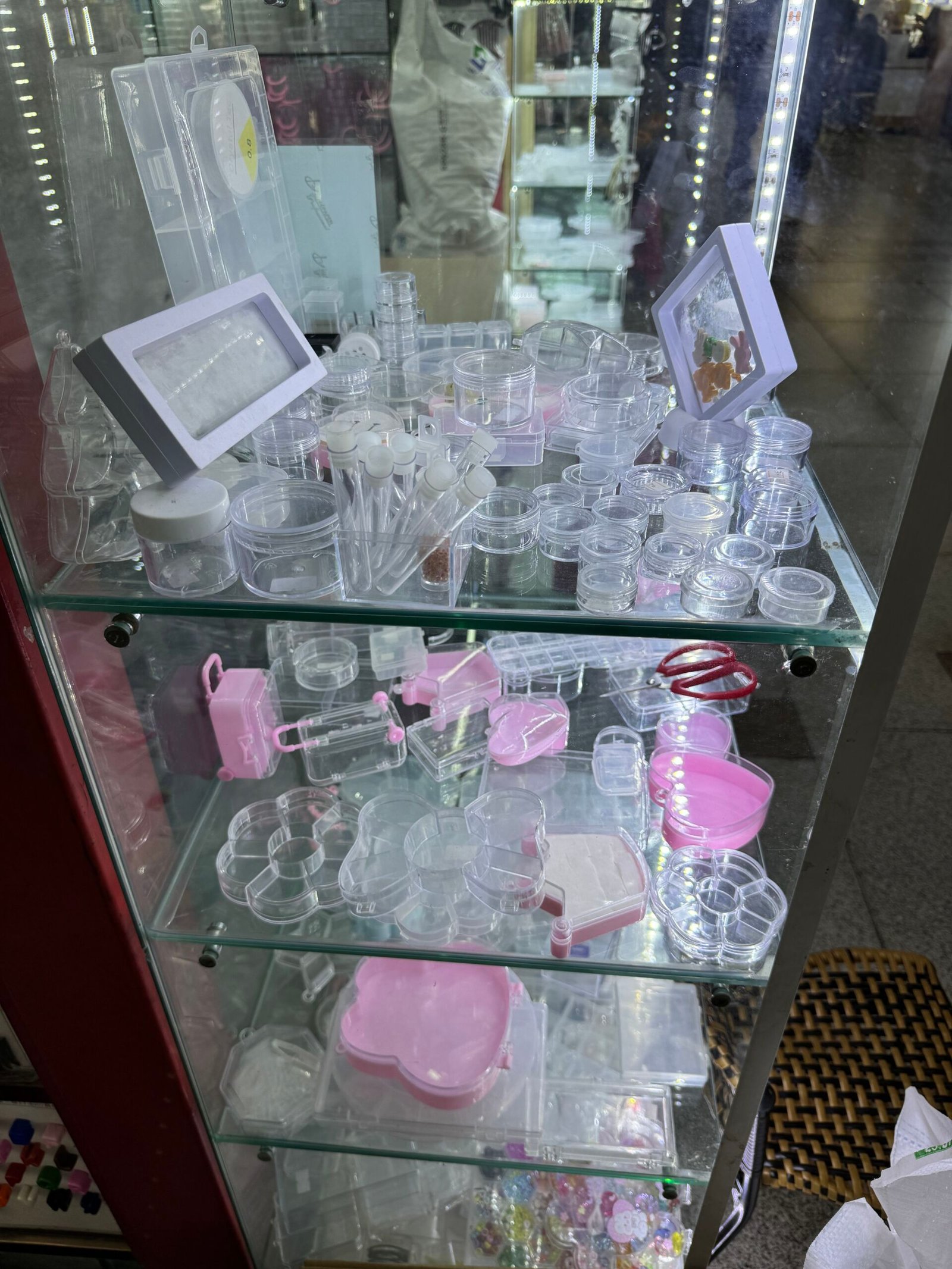 Shelf with tiny screw-top jars, sample vials, hinged mini cases, and heart-shape boxes, in Yiwu Jewelry Accessories Market, China