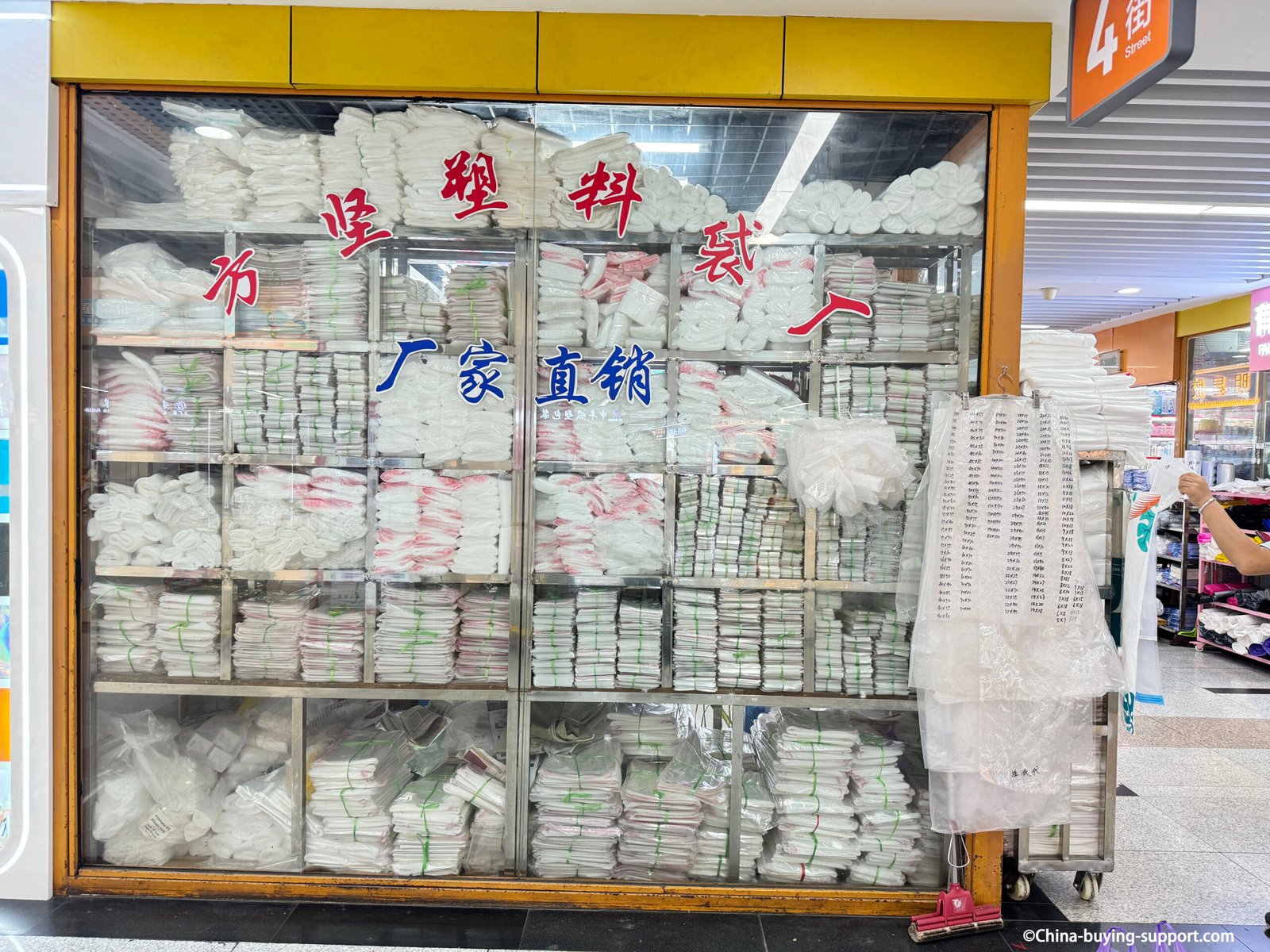 Stacked white / clear plastic bags displayed in a factory-direct wholesale store at Yiwu International Trade City District 2, showing bulk polyethylene packaging for retail and industrial use.
