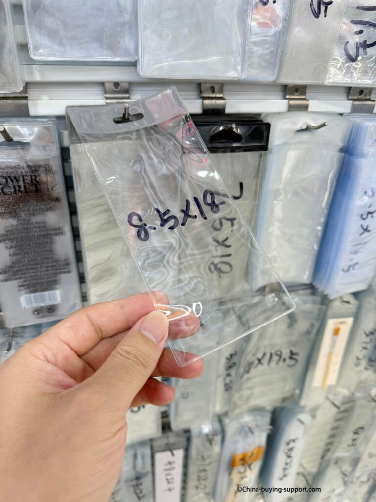 Close-up of a PVC transparent bag labeled 8.5x18, showing clear plastic packaging sample at Yiwu International Trade City Zone 2 gift packaging section.