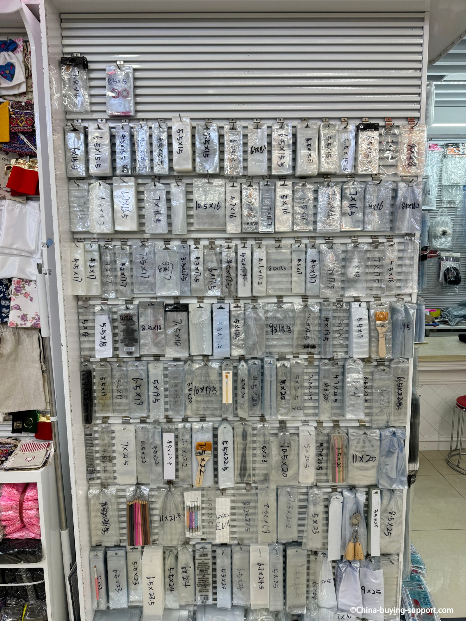 PVC transparent plastic bags display at Yiwu International Trade City Zone 2, showing multiple bag sizes for stationery, brushes, and gift packaging from a Chinese wholesale supplier.
