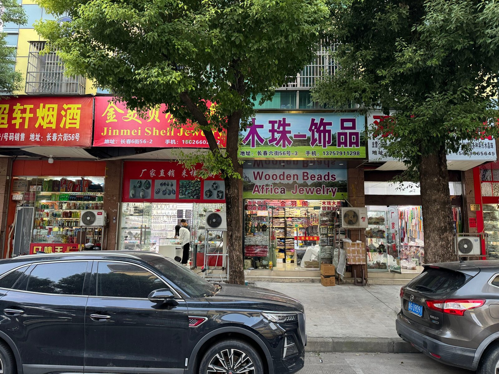 Yiwu storefront sign “Wooden Beads Africa Jewelry” on Changchun Street; display of strands and DIY parts including wood beads, cords, pendants, spacers, tassels, chains, clasps.