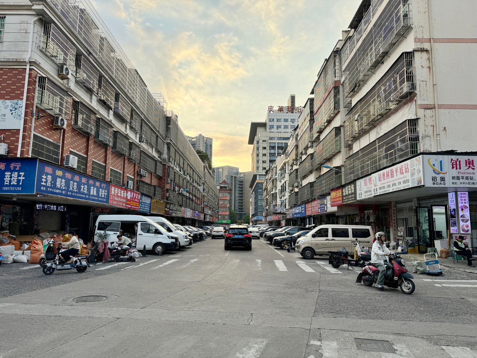 Sunset over Yiwu Xingzhong Jewelry Accessories Street with wholesale jewelry parts shops, cars, selling chains, beads, clasps and DIY findings. Yiwu China