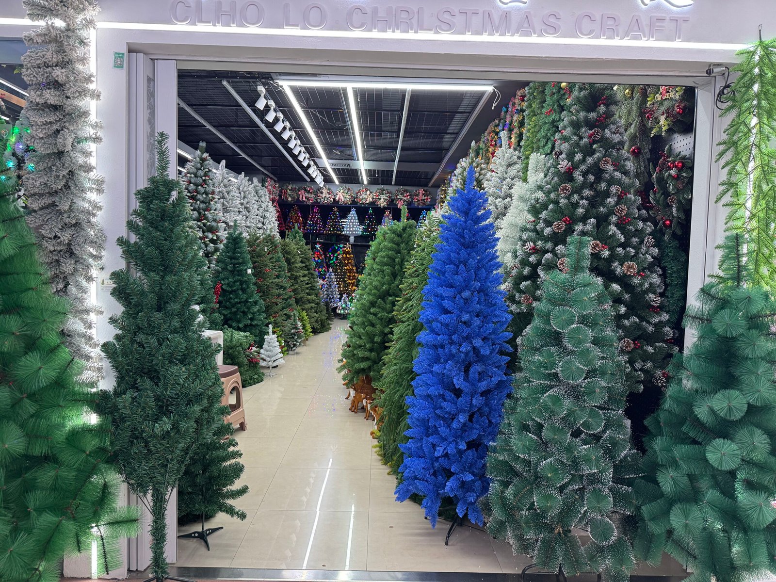 Artificial Christmas trees in many sizes and colors lined up inside a Yiwu Christmas wholesale showroom.