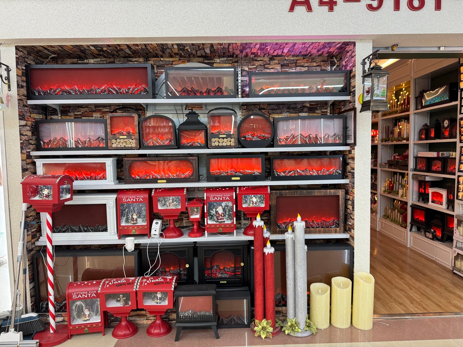 Electric fireplaces with red ember displays and red Letters for Santa mailboxes arranged on shelves in a Yiwu Christmas wholesale shop.