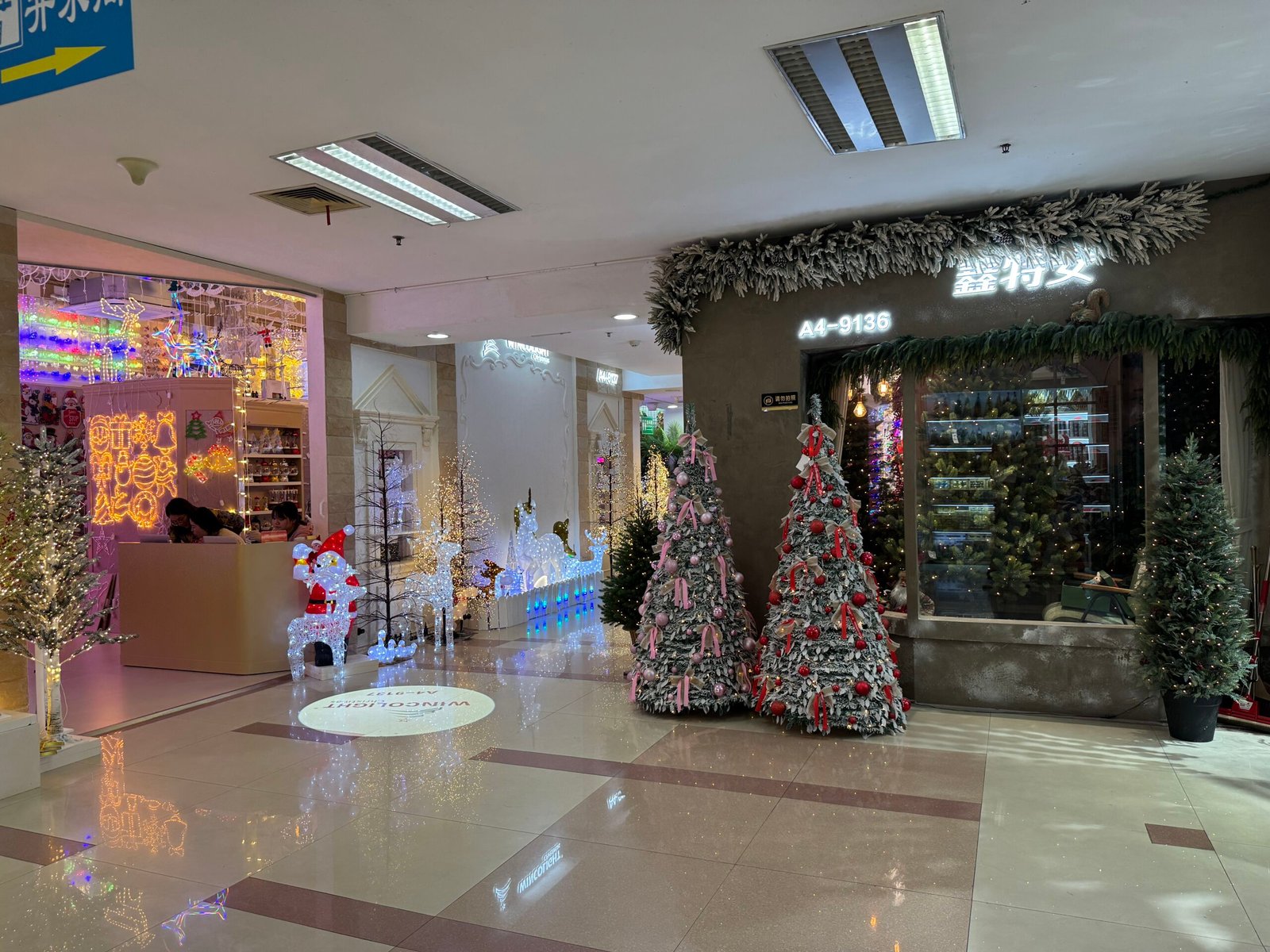 LED Christmas trees and glowing acrylic reindeer figures outside a lighting decorations shop in Yiwu Christmas market.