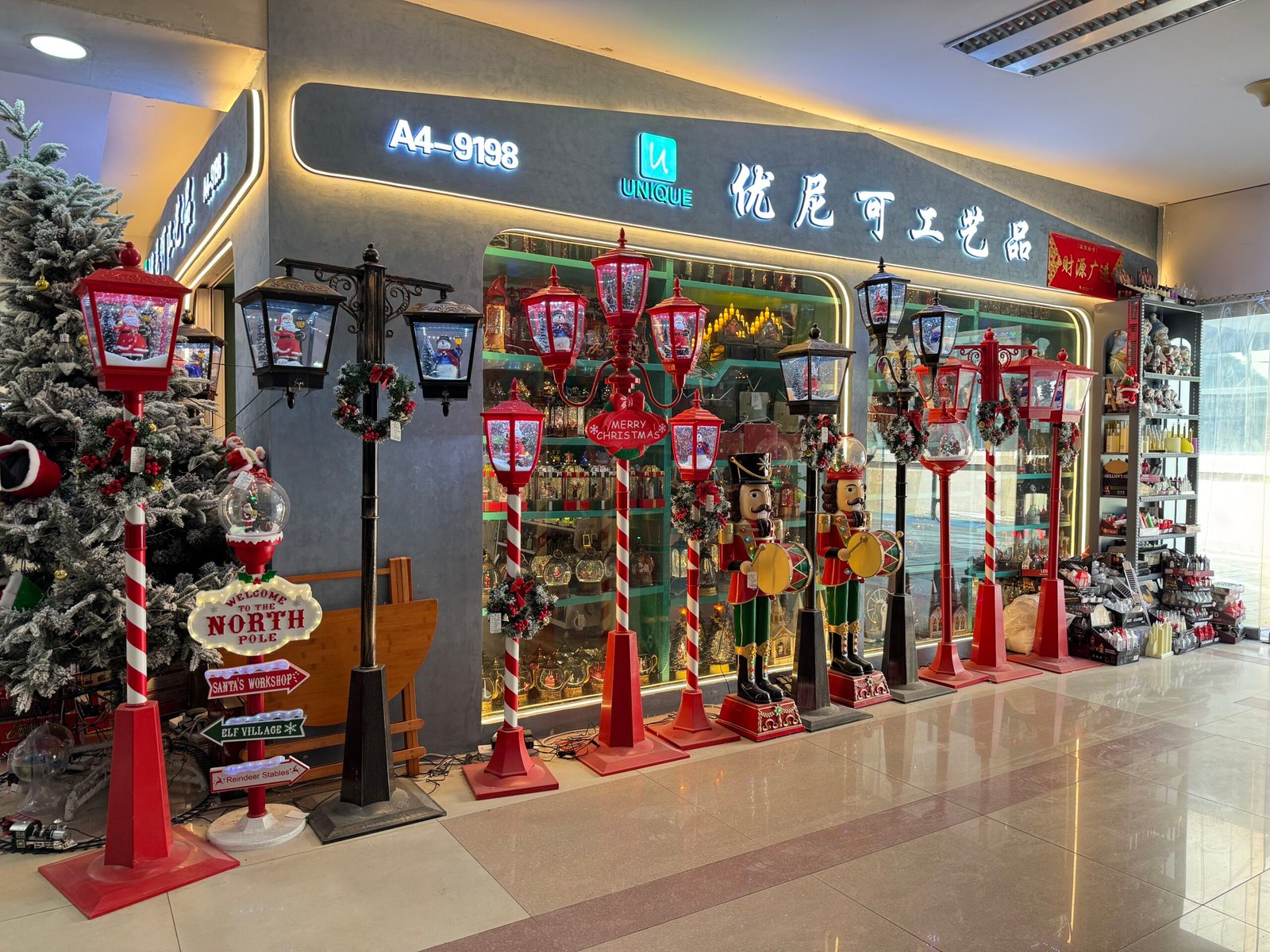 Yiwu Christmas market storefront with red and black decorative lamp posts, nutcracker statues and wreaths arranged along the aisle.