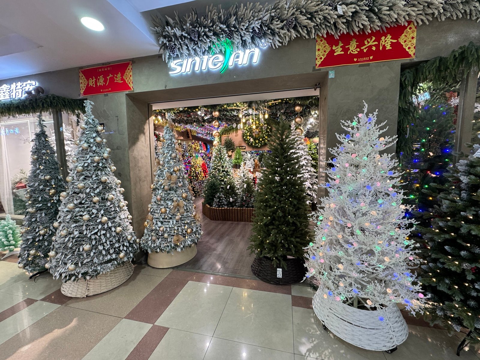 Sintean Christmas storefront in Yiwu with snowy artificial trees, white LED tree and green Christmas trees on display