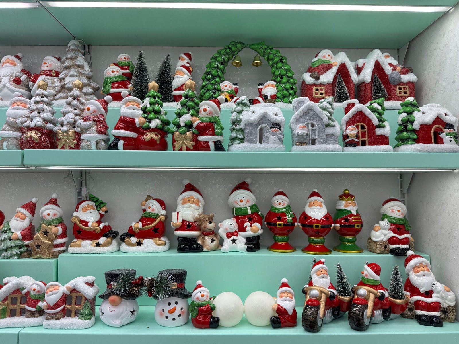 Ceramic Santa, snowman and Christmas village figurines displayed on turquoise shelves at a Yiwu Christmas decorations supplier.