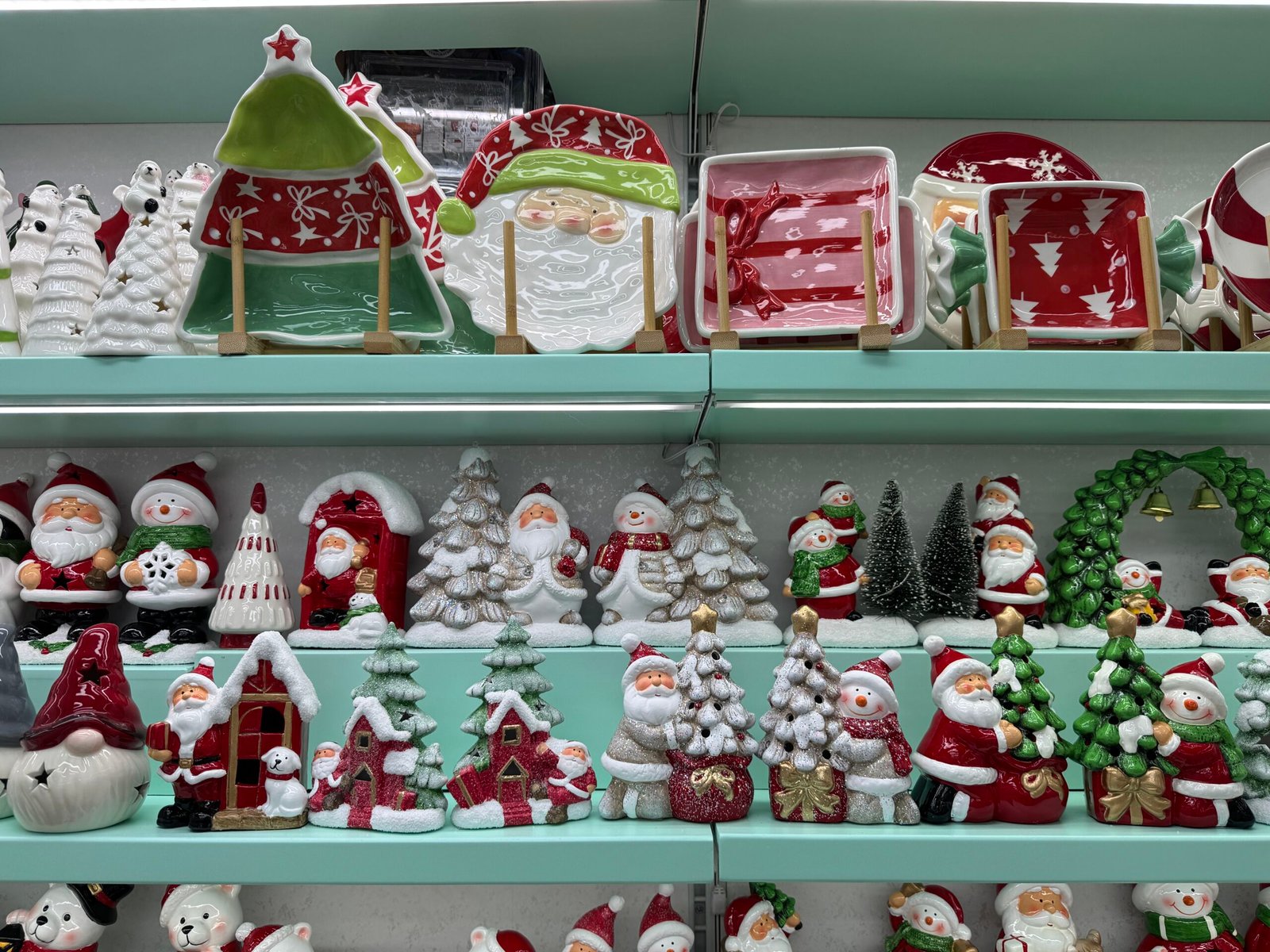 Shelves with Christmas ceramic plates on the top and Santa, snowman and tree figurines below in a Yiwu holiday tableware shop.