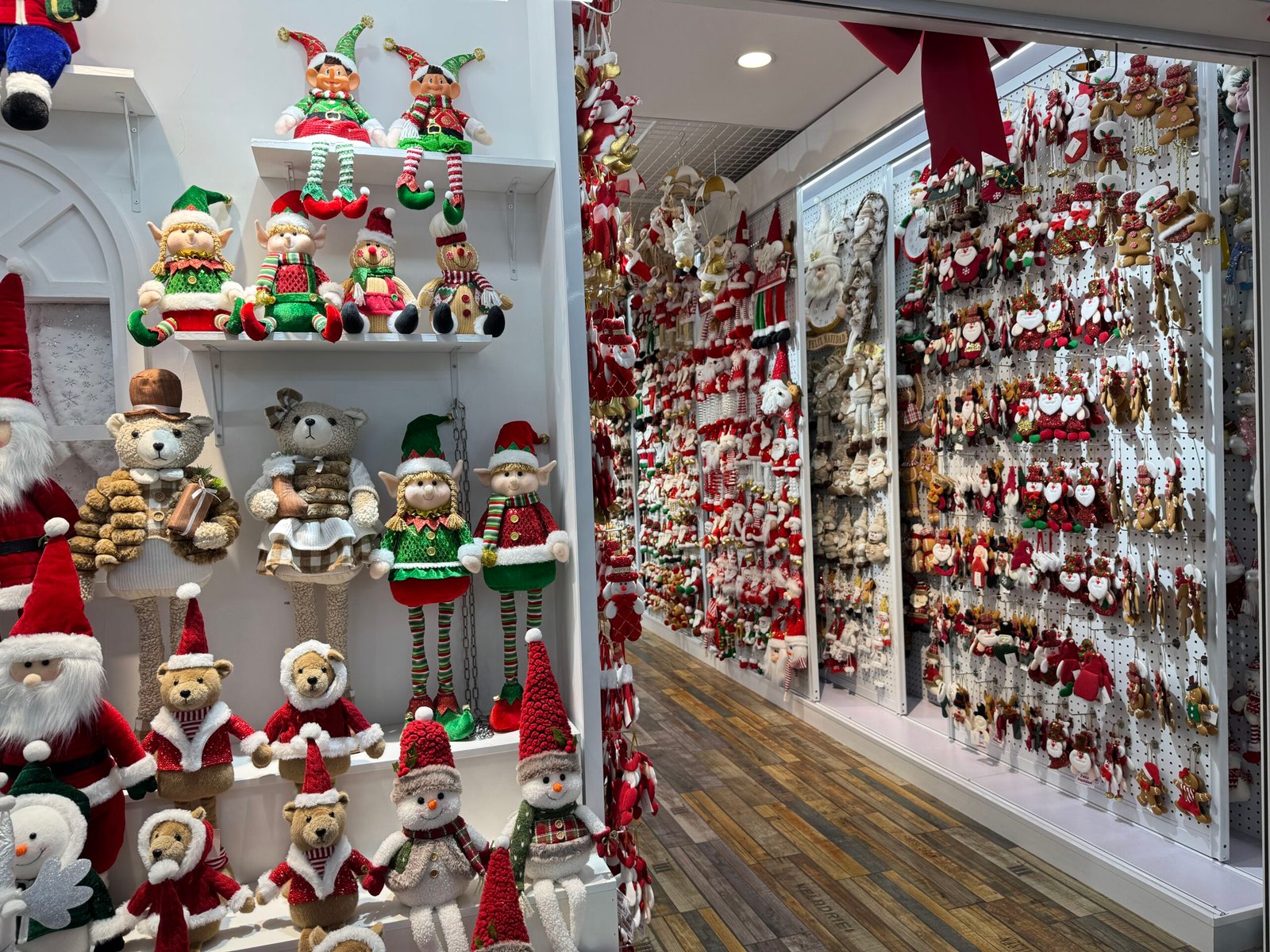 Christmas elf dolls, bears and snowman plush ornaments on shelves and pegboard wall at a Yiwu Christmas wholesale shop