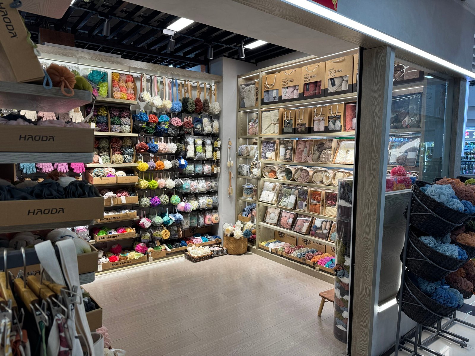 Bath accessories shop in Yiwu International Trade City District 4 with walls covered in hanging shower puff, bath sponges, loofahs, scrub gloves and neatly boxed towel gift sets.