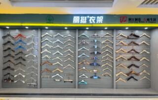 Showroom wall in Yiwu International Trade City District 4 with neatly arranged rows of wooden, metal and plastic clothes hangers under illuminated signage.