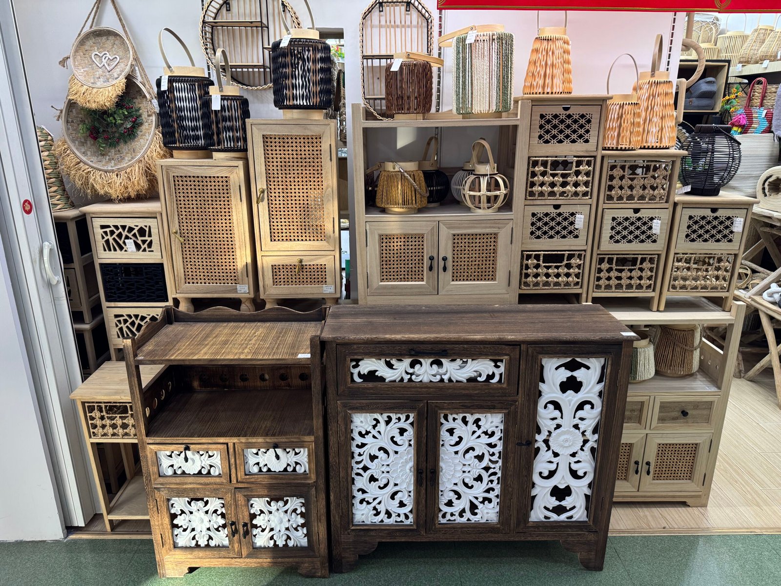 Yiwu decor shop featuring cane-front cabinets, woven drawer units, and dark wood sideboards with white carved panels and rattan lanterns on top.