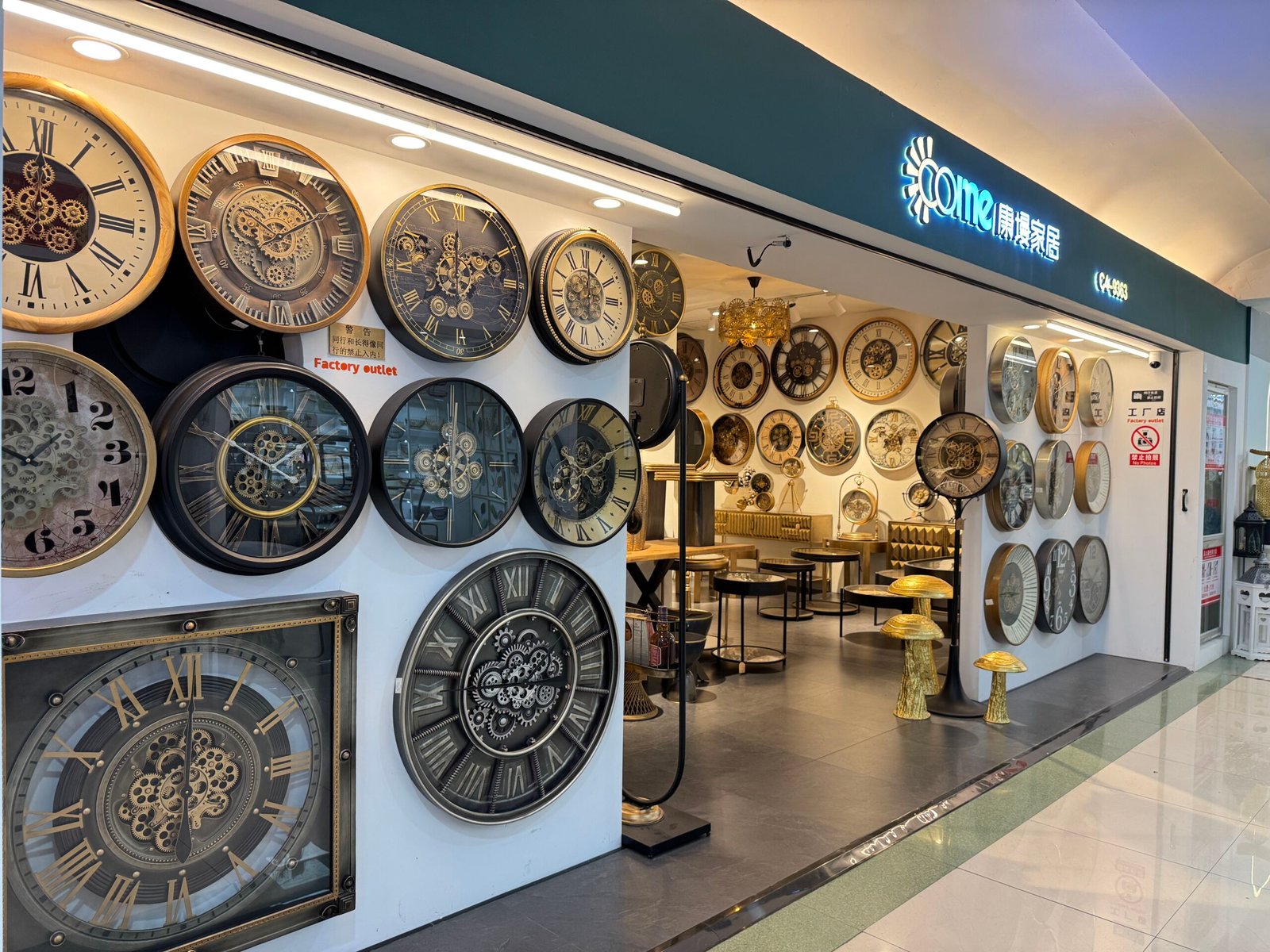 Factory outlet shop in Yiwu home decor market with its exterior wall filled with large industrial gear wall clocks in black, gold, and bronze finishes.