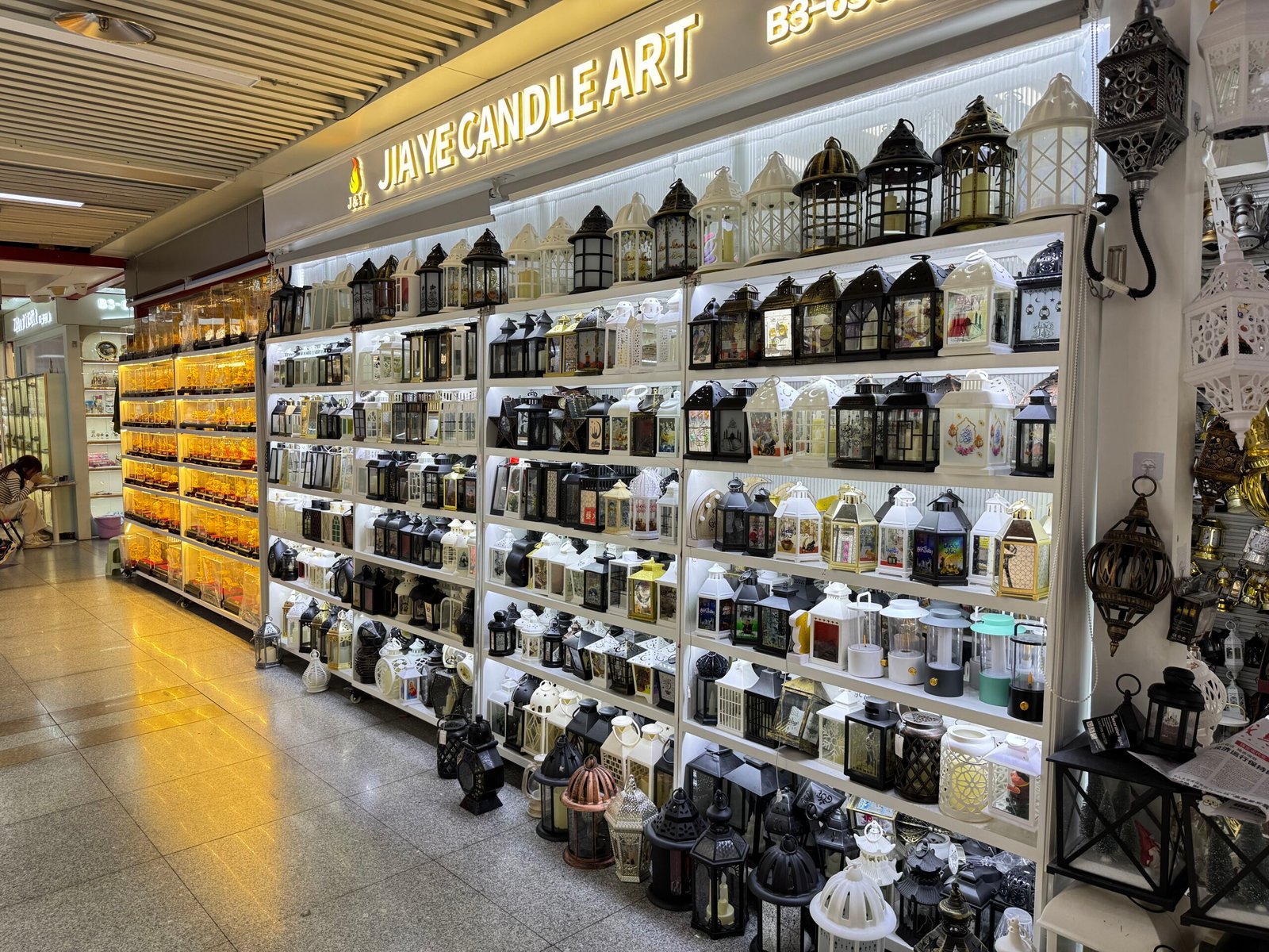 Rows of metal and glass candle lanterns in different styles filling a brightly lit shop at Yiwu home decor market.