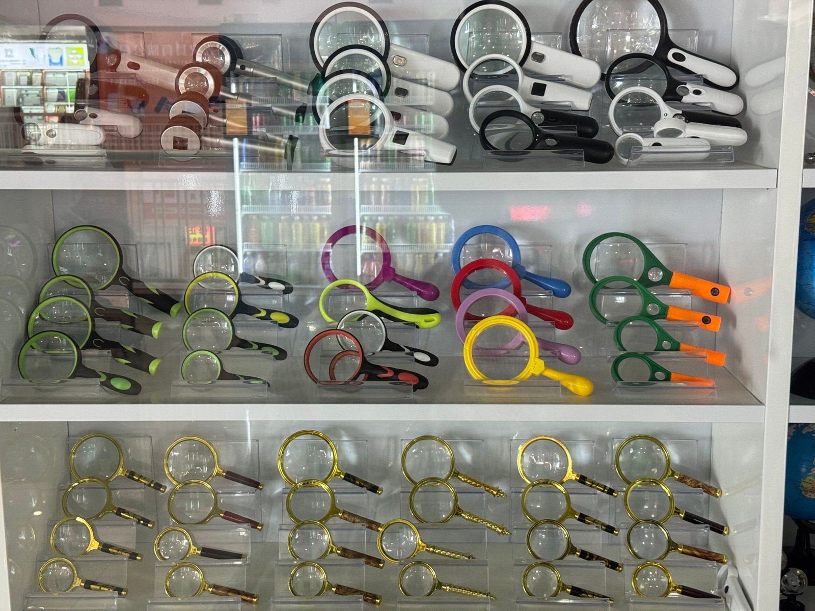 Shelves of white LED magnifiers, colorful rubber-handled magnifying glasses and traditional gold magnifiers in a glass cabinet at a Yiwu shop.