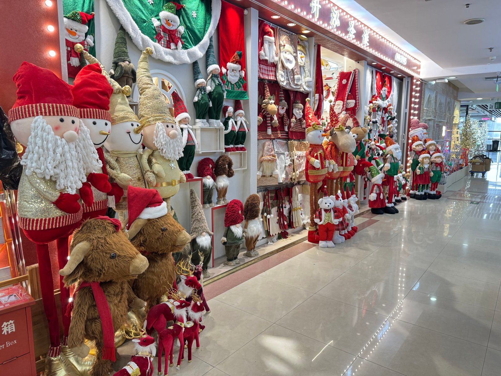 Storefront lined with large plush Santas, reindeer, snowmen and gnomes at Yiwu Christmas wholesale market.