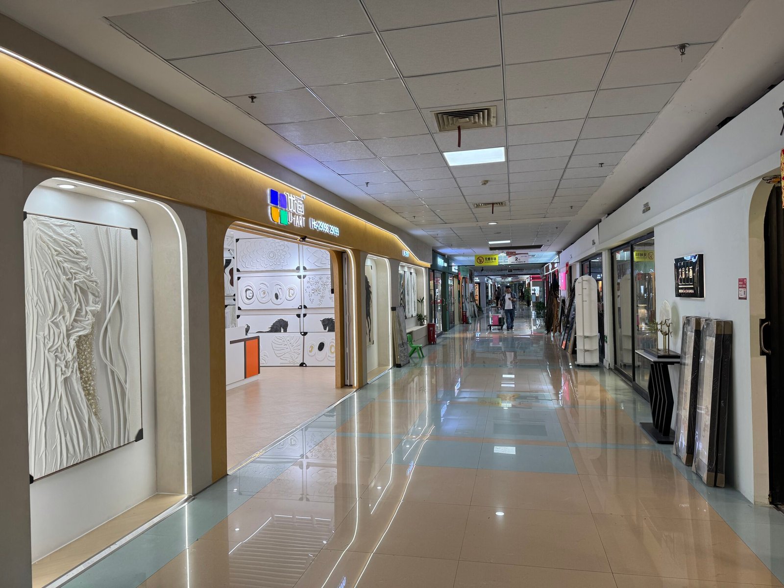 Exterior of U-ART decorative painting store along the polished corridor of Yiwu International Trade City District 3 5F, with large textured wall art displayed at the entrance.