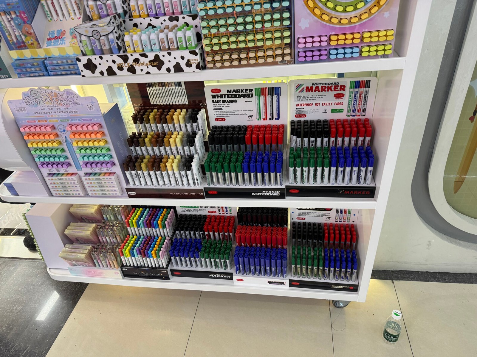 Shelves filled with assorted whiteboard markers, wood-grain paint pens and pastel block highlighters in a stationery shop in Yiwu International Trade City District 3.