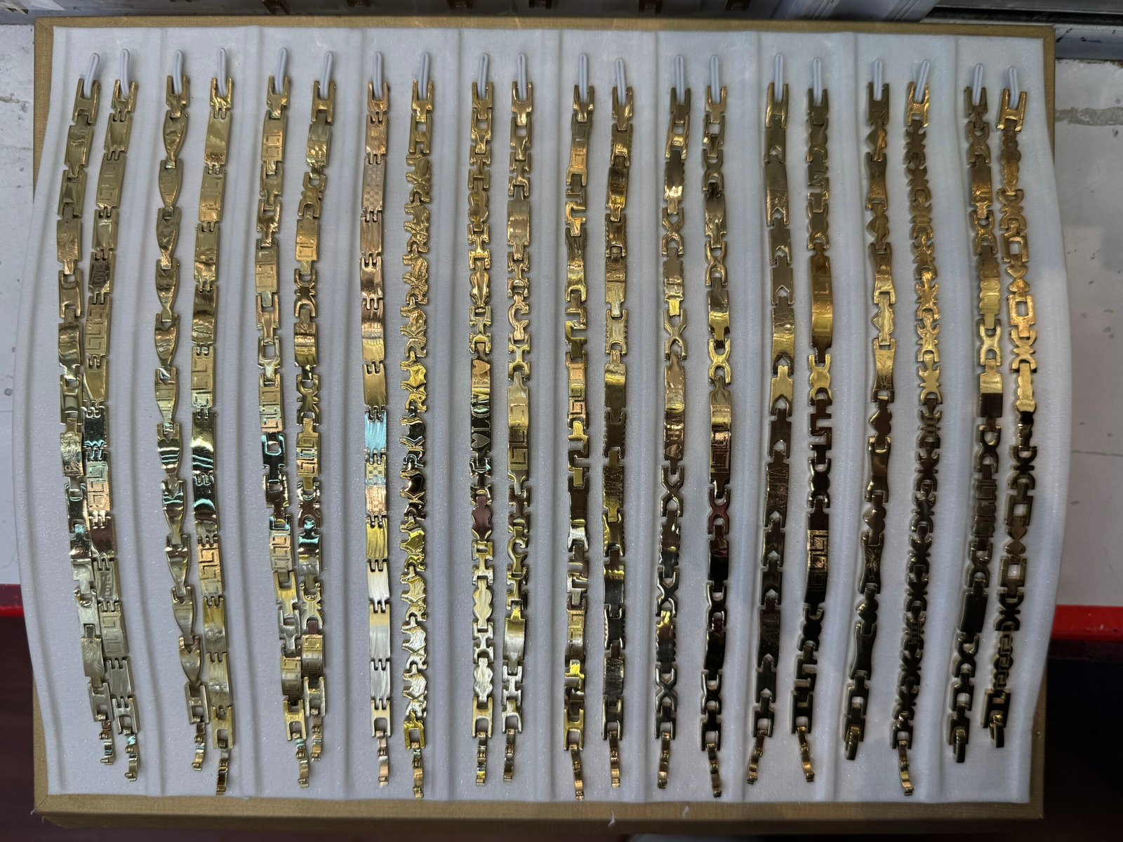 Copper gold plated bracelet chains with Greek key and geometric links displayed in a wholesale sample tray