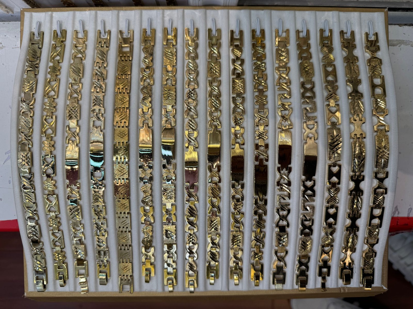 Textured diamond-cut copper gold plated bracelet chains displayed side-by-side in a wholesale sample tray